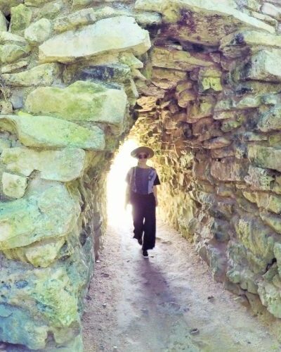 Tourist walking along a pathway surrounded by ancient Mayan ruins in Tulum, entering a historic Mayan world.