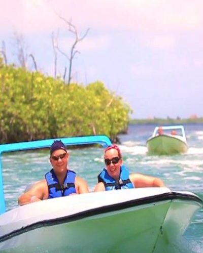 Couple smiling and enjoying a jungle tour by boat, surrounded by lush vegetation and crystal-clear waters.