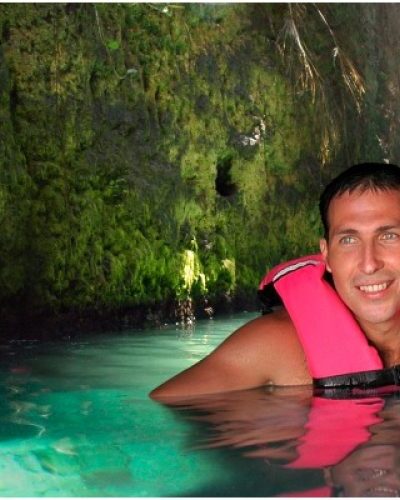 Visitors swimming through a winding underground river, enjoying a peaceful adventure at Xcaret Park.