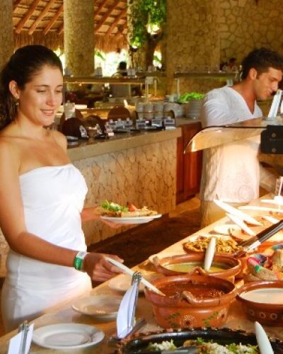 Dining area at Xcaret Park with lush greenery and rustic decor, offering guests a relaxing meal experience.