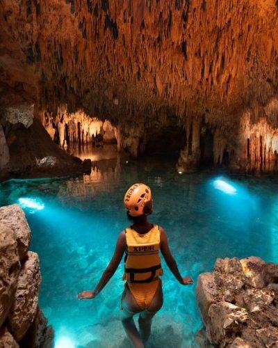 Swimmer floating in a tranquil underground river surrounded by stunning rock formations at Xplor Park.