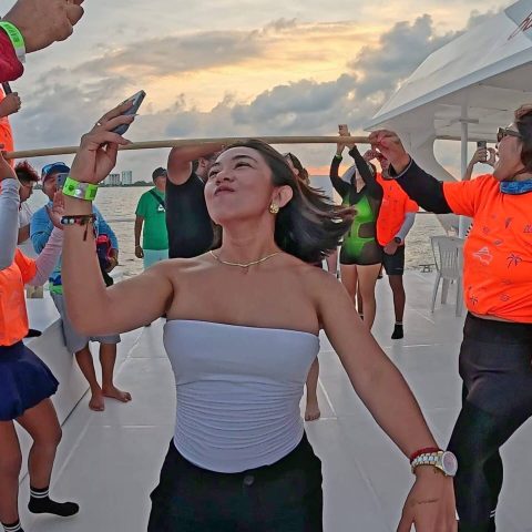 Smiling girl dancing and taking a selfie after passing the limbo contest on the Baby Dancer catamaran in Cancun