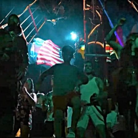 Nighttime show on the Jolly Roger pirate ship, with lights illuminating the performance against the night sky in Cancun Bay.