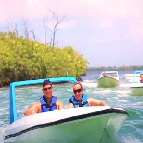 Couple smiling and enjoying a jungle tour by boat, surrounded by lush vegetation and crystal-clear waters.