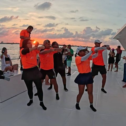 Entertainment staff dancing on board, sunset behind