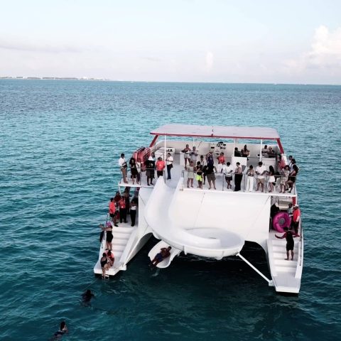 Guests enjoying the water slide from the Baby Dancer catamaran into the Caribbean Sea in Cancun