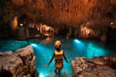 Swimmer floating in a tranquil underground river surrounded by stunning rock formations at Xplor Park.